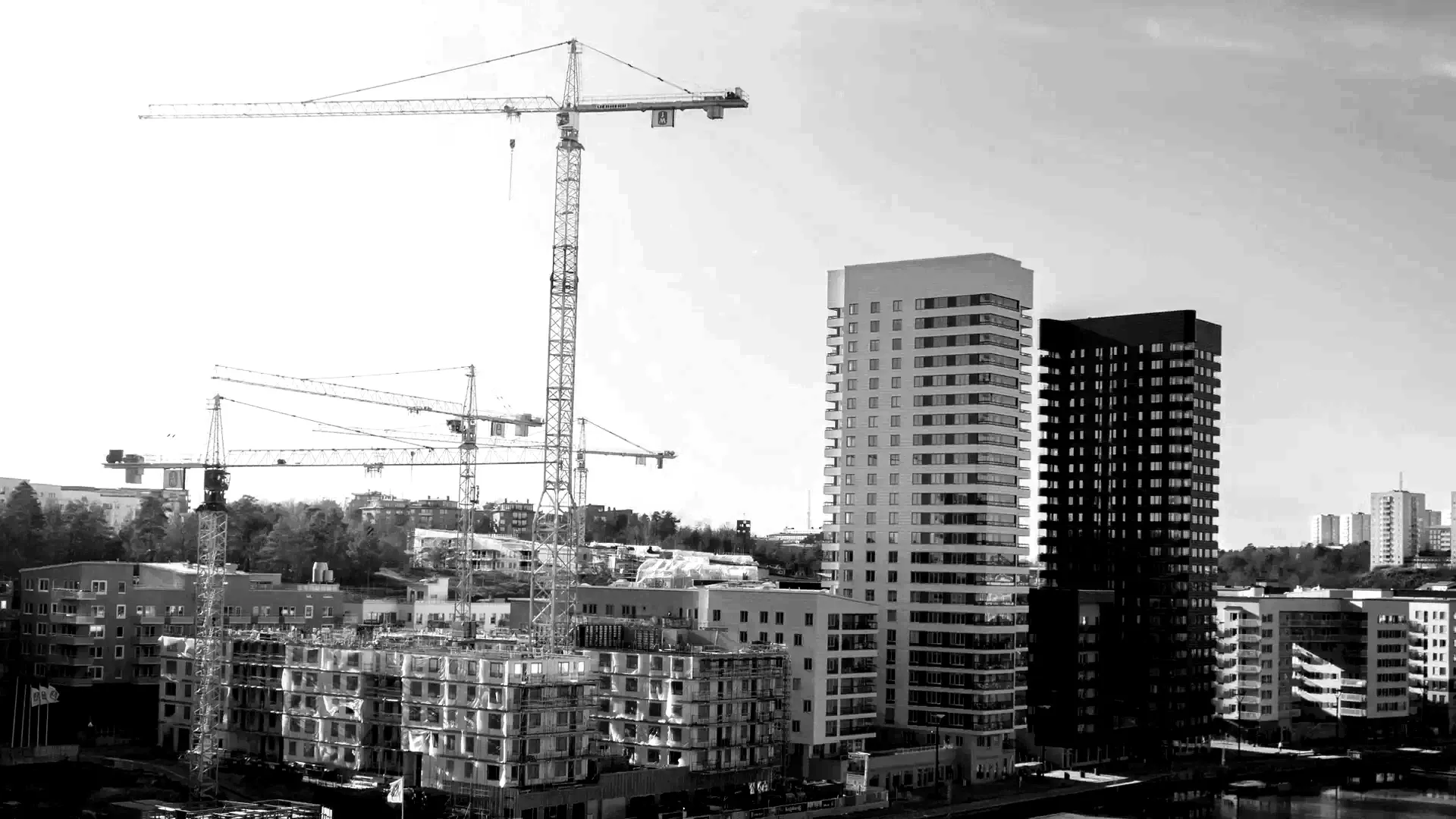 Byggarbetsplats i Stockholm med lyftkranar och betongstommar under uppförande.